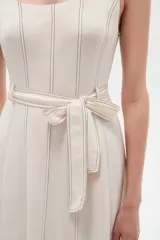 Vestido midi de lino color blanco con cuello cuadrado, sin mangas, detalle de pespuntes a contratono y cinturón con hebilla integrada en la cintura.