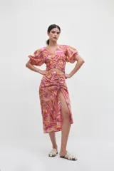 Blusa crop top rosada con estampado floral en tonos amarillos, naranjas y blancos, con escote en V, mangas abullonadas cortas y detalle de aro forrado en el centro del pecho con fruncidos.