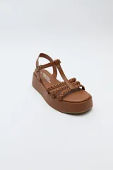 Sandalia de plataforma color marrón con tiras trenzadas y pulsera con hebilla.