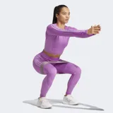 Remera corta de entrenamiento Adidas de color lila, con diseño sin costuras y ajuste ceñido. Posee cuello redondo, mangas largas con las tres tiras características de la marca y dobladillo acanalado.