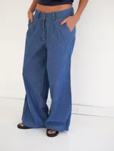 Pantalón palazzo de denim azul claro con pinzas en la cintura, bolsillos laterales y cierre frontal con botón.