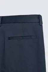Pantalón chino de corte regular fit, confeccionado en tejido de algodón con elasticidad. Presenta bolsillos frontales, bolsillos traseros de vivo y cierre frontal con cremallera y botón.