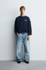 Sudadera boxy fit color azul marino, confeccionada en tejido rib, con cuello redondo y manga larga. Presenta un estampado blanco en el delantero con el texto "The Best Version".