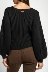Cardigan negro de algodón con cuello en V, cierre frontal de botones y mangas largas con textura calada. Presenta puños y ruedo acanalados.