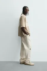 Sudadera de corte relajado, color beige claro, con cuello redondo y manga corta. Presenta un estampado frontal con texto en blanco difuminado que dice "SCREEN PLAYER" y debajo "Hypercore Technology".