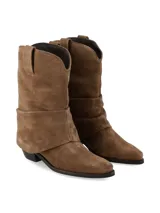 Bota de caña media confeccionada en gamuza color marrón, con diseño de pliegues naturales y caída suave. Presenta punta afinada y taco acuñado, con un estilo inspirado en la estética western.