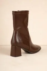 Botas negras de caña media en símil cuero, con cierre lateral y punta redondeada. Taco cuadrado de 6,5cm de alto.