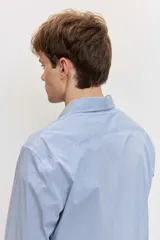 Camisa celeste de manga larga con cierre frontal de botones y cuello clásico.