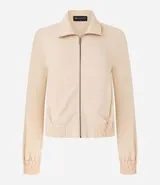 Campera bomber femenina color beige claro, confeccionada en tejido Airflow texturado. Presenta cuello solapa, cierre frontal de cremallera y puños y bajo elásticos.