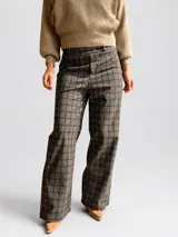 Pantalón sastrero de corte recto y tiro medio-alto, con estampado de cuadros en tonos grises y marrones. Presenta una cintura elástica que aporta comodidad y una textura de tela abrigada.