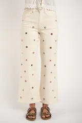 Pantalón de jean color crudo, de corte recto y tiro medio, con bordados de flores marrones.