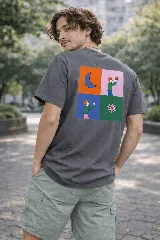 Remera manga corta color gris oscuro con un estampado gráfico en la espalda dividido en cuatro paneles: una luna creciente naranja, una figura humana sosteniendo un objeto en un fondo rosa, otra figura humana sosteniendo un objeto en un fondo azul, y una flor estilizada en un fondo verde.