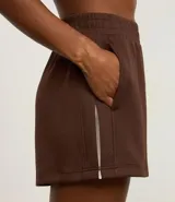 Bermuda deportiva femenina color marrón, confeccionada en modal, con cintura elástica y detalle de pliegues.