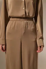 Pantalon de vestir de corte ancho y tiro alto, confeccionado en tela de viscosa con acabado satinado. Presenta cintura elástica y diseño fluido.
