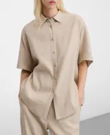 Camisa oversize color beige con diseño de microdibujo a cuadros, cuello italiano, mangas cortas japonesas y cierre frontal con botones.