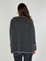 Sweater gris de manga larga con cuello redondo y puños con detalle de volados de lana rizada.
