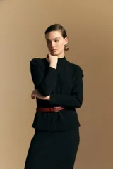 Polera de cuello alto confeccionada en tejido de punto negro, con diseño de textura acanalada en cuello, puños y ruedo, y trama vertical en mangas y espalda.