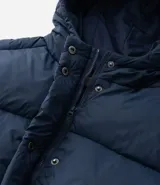 Campera puffer acolchada color azul marino, con capucha, cierre frontal con broches a presión, bolsillos laterales y cordón regulador en la cintura para ajuste entallado.
