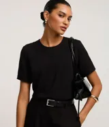 Blusa negra de manga corta, con cuello redondo y pespuntes. Confeccionada en poliéster plano con efecto airflow y abertura trasera tipo gota con cierre de botón.