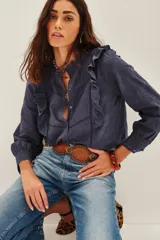 Camisa de algodón azul marino con diseño texturizado, cuello mao y volados frontales. Presenta mangas largas con puños ajustados y detalles de encaje en los bordes.