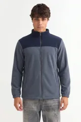 Campera de polar con cierre frontal completo, cuello alto y diseño bicolor en gris y negro. Cuenta con bolsillos laterales y puños elásticos.