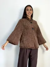 Chaqueta de textura peluda en color bordó, con cuello mao y cierre frontal con un botón grande. Presenta mangas amplias y un diseño holgado.