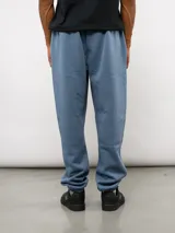 Pantalón de jogging de felpa con friza, color gris, con cintura elástica, bolsillos laterales y puños en los tobillos. Presenta un parche con el logo de Umbro en la parte superior delantera.
