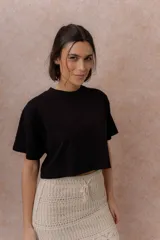 Remera crop negra de calce amplio, con cuello redondo y mangas cortas sueltas.