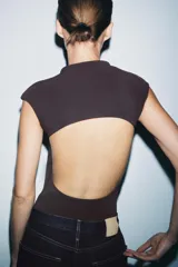 Body confeccionado en tejido elástico color crudo, con cuello redondo, manga sisa y detalle de cut out en la espalda.