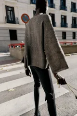 Jersey de punto color marrón oscuro con lentejuelas plateadas, cuello barco y manga larga acampanada.