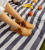 Zapato acordonado de cuero vacuno con acabado desgastado, de horma cuadrada y suela de goma con pequeño taco.