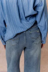 Pantalón de jean con tiro alto y corte wide leg, de color azul con efecto desgastado. Cuenta con cierre y botón frontal, además de bolsillos funcionales.