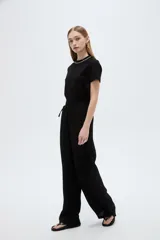 Pantalón negro de poliéster, con bolsillos laterales, tiro alto y diseño ancho.