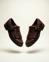 Mocasín de cuero color bordó con textura trenzada en la puntera. Presenta una solapa desmontable con flecos y detalle de perforaciones, junto con una hebilla lateral metálica. Diseño versátil que permite transformar el calzado.