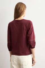 Remera bordó de manga larga con detalles en popelina en las mangas y costuras visibles en contraste.