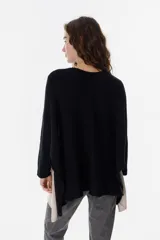 Poncho de tejido de punto con diseño oversize y aberturas laterales. Presenta un acabado con destellos brillantes y cuello redondo amplio.