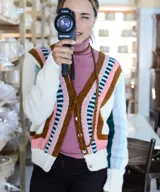 Cardigan tejido a mano en lana merino, con diseño multicolor de bloques geométricos y rayas en tonos blanco, marrón, rosado, celeste y verde. Presenta escote en V, mangas largas y cierre frontal con botones.
