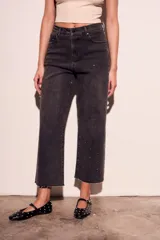 Pantalón de jean negro con efecto gastado y pequeños brillos. Corte recto, tiro alto y terminación desflecada.