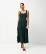Vestido midi de corte evasé, color verde oscuro, con escote cuadrado, breteles anchos y recortes verticales que definen la silueta.