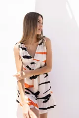 Vestido corto blanco con estampado abstracto en negro y naranja, escote en V y tirantes finos con lazo.