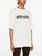 Remera blanca de algodón con estampa frontal de la frase "New York" en letras negras difuminadas y logo de la marca Anine Bing.