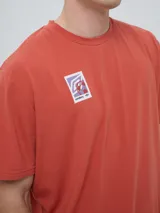 Remera de manga corta color beige, con cuello redondo y diseño holgado. Cuenta con un pequeño estampado rectangular en el pecho con motivo futbolero.