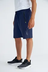 Short deportivo negro con cintura elástica ajustable con cordón, bolsillos laterales con cierre y detalles en verde flúor.