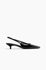 Zapatos destalonados negros de tacón kitten, con punta fina, tira elástica en el talón y acabado brillante.
