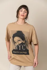 Remera color beige con estampado de una mujer con anteojos y la inscripción "NYC Beauty Leopaid" con apliques de strass.