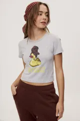 Remera blanca de manga corta, con estampa frontal de un pato de hule con turbante y labios pintados, acompañada de la frase "In all else fails, denial".