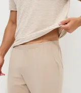 Pijama para hombre compuesto por una remera de manga corta con cuello redondo y estampado de rayas horizontales finas, y un pantalón largo liso con cintura elástica.