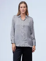 Camisa de satén estampado con diseño de cadenas en blanco y negro. Cuello con solapa, escote en V y abertura central con botones.