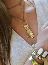 Collar con cordón de cuero fino y dije de bronce con diseño orgánico y textura irregular, sujeto por una argolla metálica.