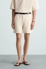 Bermuda de algodón color blanco, de corte relajado, con cintura elástica, bolsillos frontales y bolsillos traseros de plastrón. Cierre frontal con cremallera y botón.